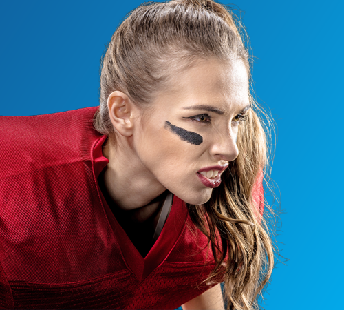 Paradenti bambini su una giocatrice di football americano in uniforme rossa, ritratta in primo piano su sfondo blu mentre indossa protezioni sportive