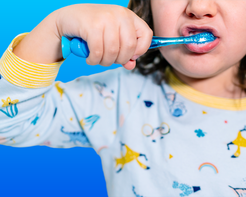 Igiene orale bambini immagine che mostra un bambino mentre si lava i denti con energia, utilizzando uno spazzolino blu e indossando un pigiama colorato, a rappresentare l’importanza di una corretta pulizia quotidiana fin dalla prima infanzia.