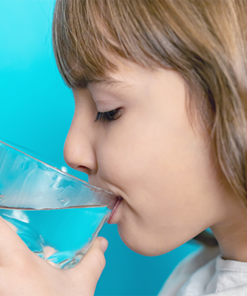 fluoroprofilassi infantile mostra una bambina bere acqua arricchita di fluoro come parte della prevenzione dentale infantile.