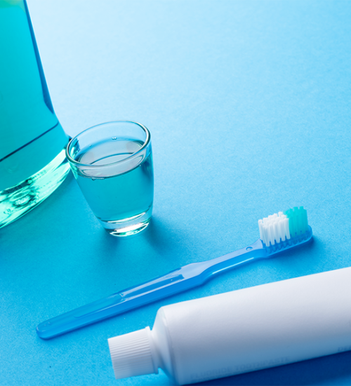 fluoroprofilassi infantile mostra come risciacquare la bocca con collutorio al fluoro accanto a spazzolino e dentifricio.