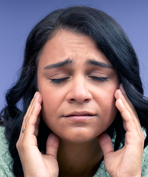 Terapia ortodontica per adulti evidenzia una donna adulta che tocca le tempie per il dolore causato da problemi mandibolari
