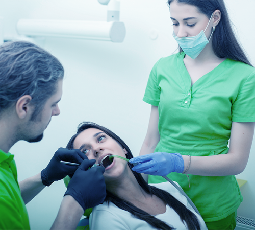 Ricostruzione dentale estetica evidenzia una paziente adulta assistita da due professionisti mentre viene eseguito un trattamento odontoiatrico volto a ripristinare estetica e funzionalità del dente