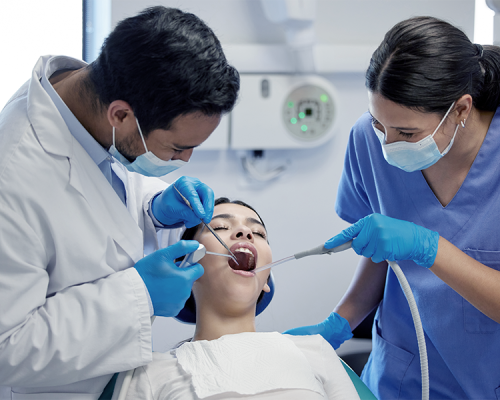 Trauma dentale riparato da un dentista e un’assistente mentre trattano una paziente seduta sulla poltrona odontoiatrica