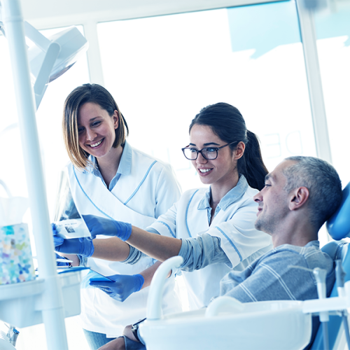 igiene orale adulti eseguito da un team di dentisti che mostra un’immagine diagnostica a un paziente adulto durante una visita di prevenzione