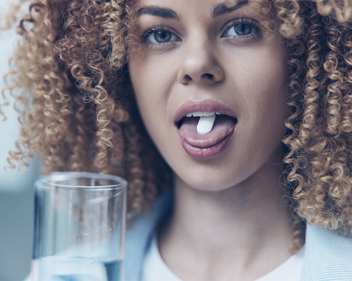 Fluoro profilassi adulti evidenzia una donna adulta che assume un integratore di fluoro con un bicchiere d’acqua